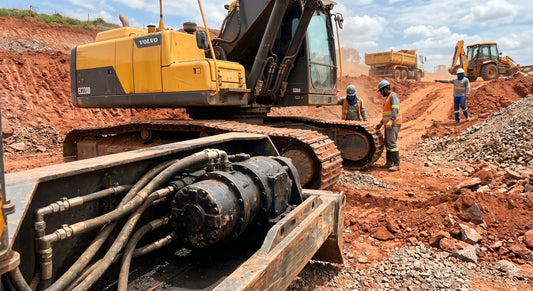 A hydraulic motor powering a yellow excavator on a construction site.