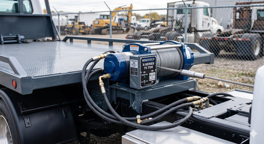 Heavy-duty hydraulic winch mounted on a flatbed tow truck.